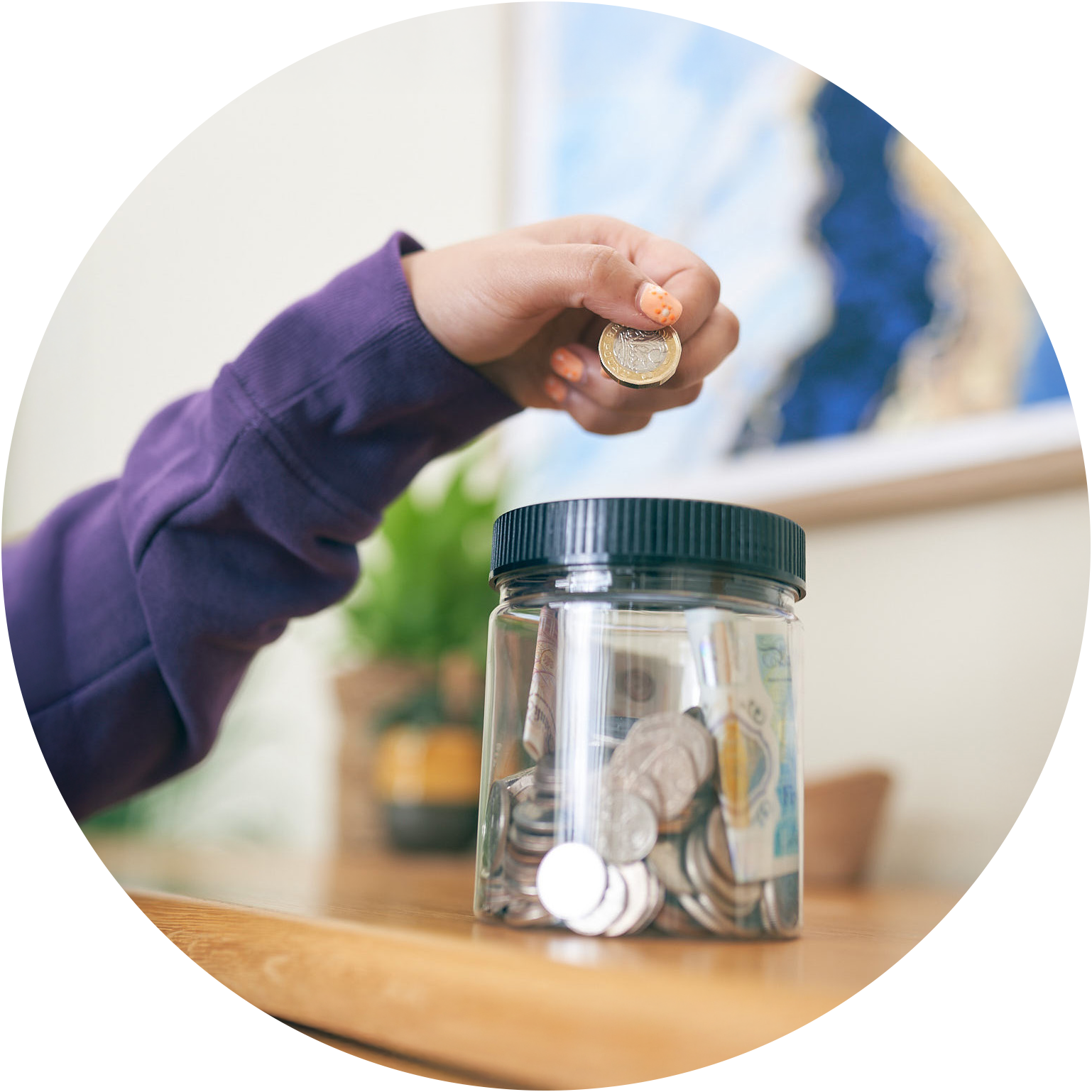 Hand putting a coin into a money pot which is half full